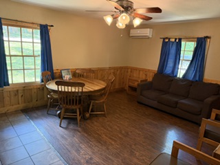 Living room with round table, chairs, sofa, and blue curtains.