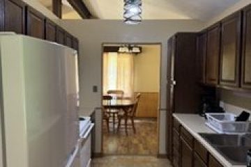 Kitchen with wooden cabinets and dining area visible through doorway.