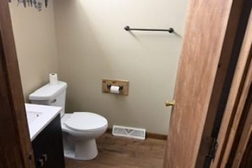 Bathroom with a toilet, sink, and toilet paper holder on a beige wall.