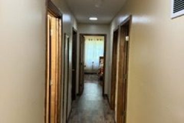 Long hallway with wooden floor and beige walls.