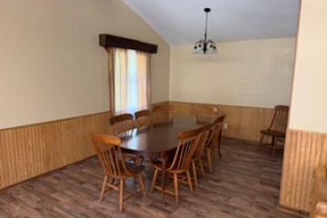 Dining room with wooden table, eight chairs, and chandelier.