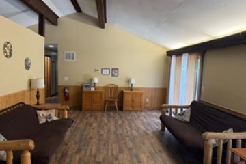 Living room with wooden floors, two brown futons, and a wooden desk with a chair.