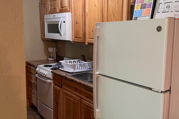 Small kitchen with wooden cabinets, white appliances, and tiled floor.