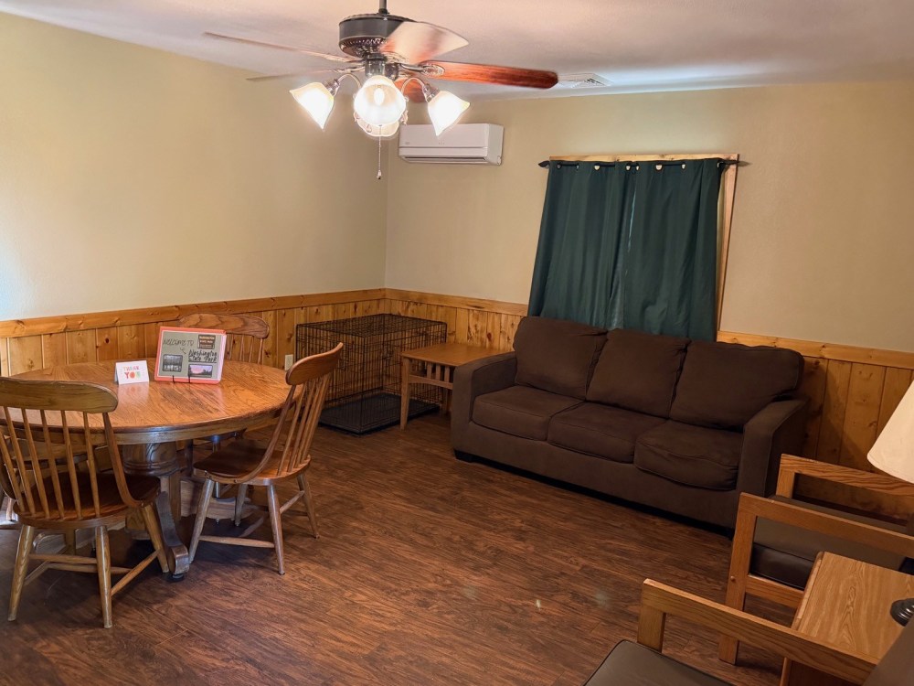 Living room with a sofa, dining table, chairs, and a ceiling fan.