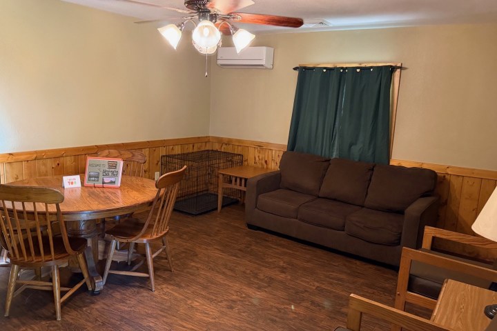 Living room with sofa, round table, chairs, and ceiling fan.