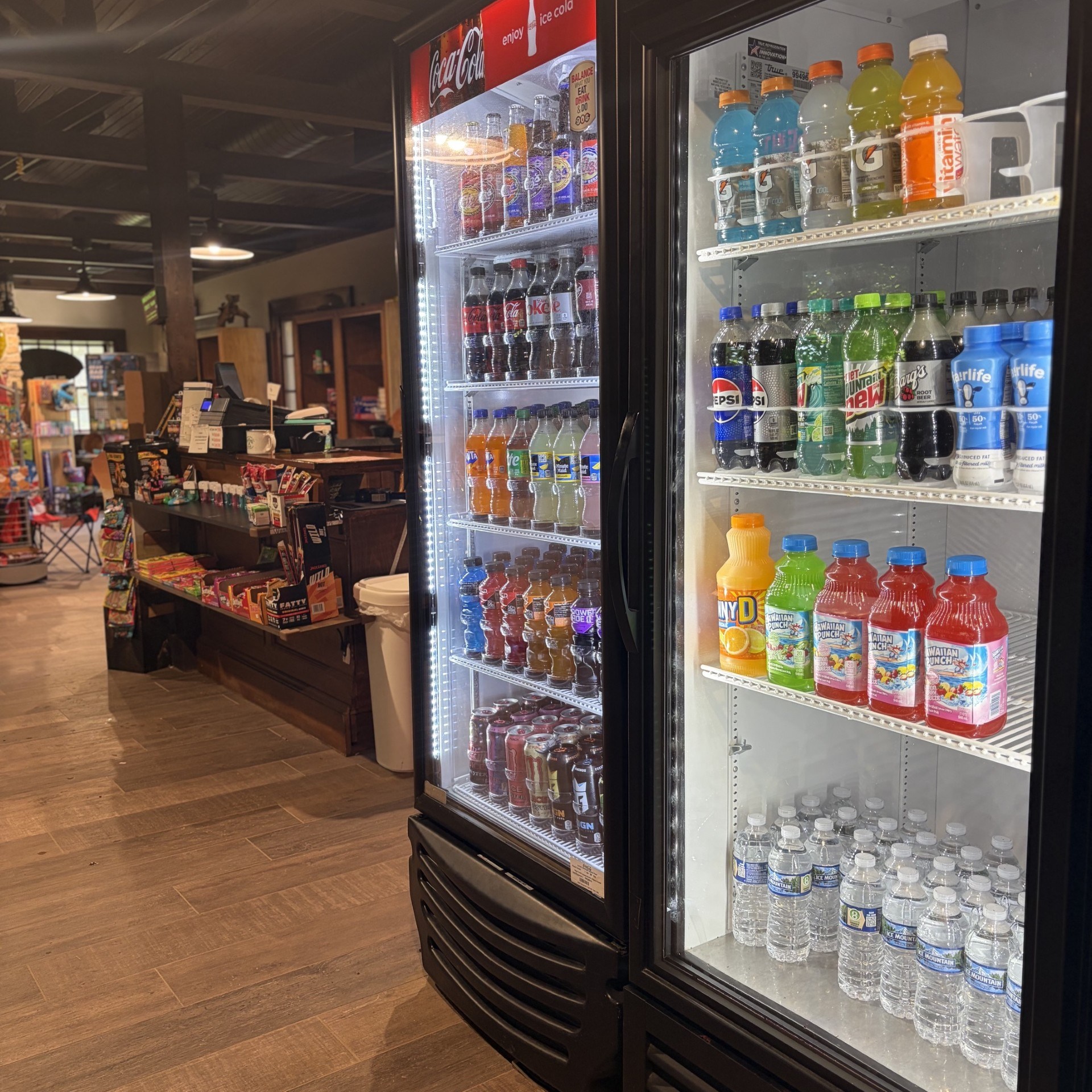 A store aisle with two beverage refrigerators filled with various drinks.