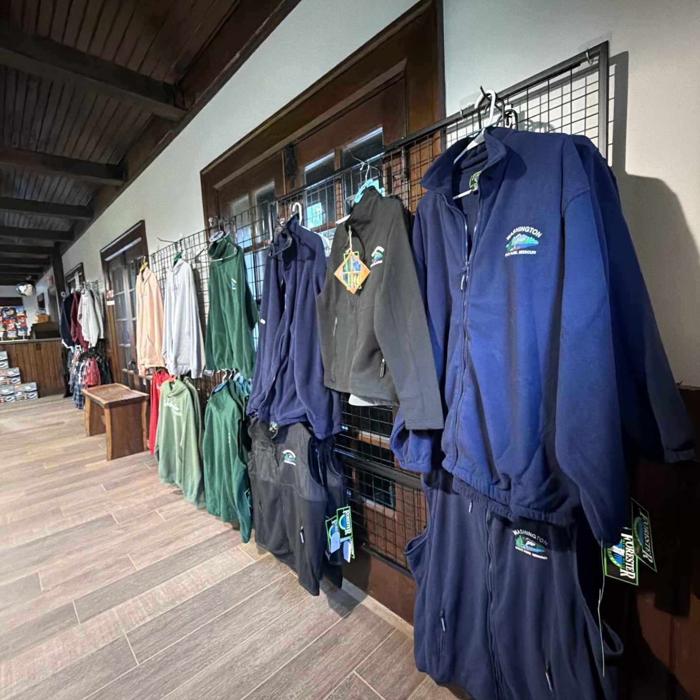 Clothes displayed on racks in a store interior with wooden ceiling.